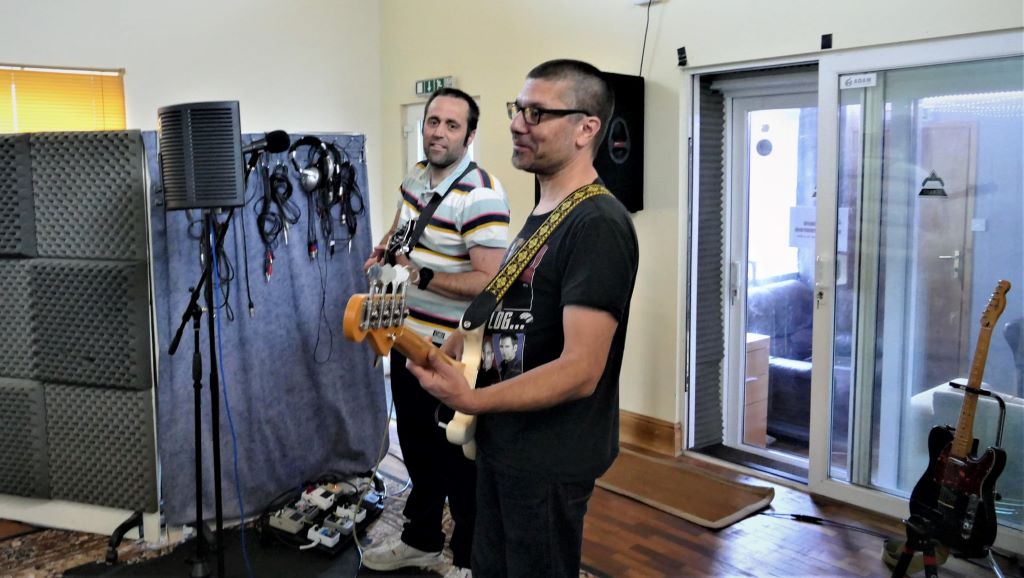 Guitarist and bassist recording in the live room